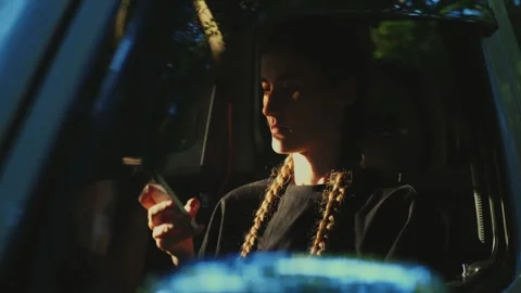Young woman using a smartphone inside a parked car illuminated... Stock Footage 341613068