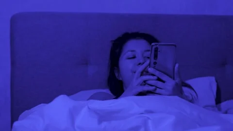 Young woman using smartphone lying in bed Stock Footage 267006014
