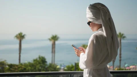 Young Woman Using Smartphone with Ocean View from Hotel Room at Dawn Видео 345275272