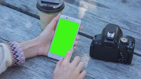 Young Woman using SmartPhone with pre-keyed green screen sitting at the table Stock Footage 74314957