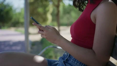 Young woman using smartphone sitting on a park bench Stock Footage 339007428