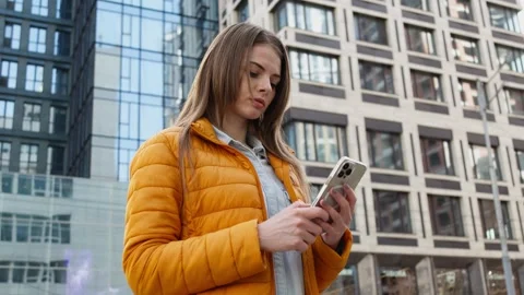 A young woman using smartphone in a spring city. Stock Footage 273015416