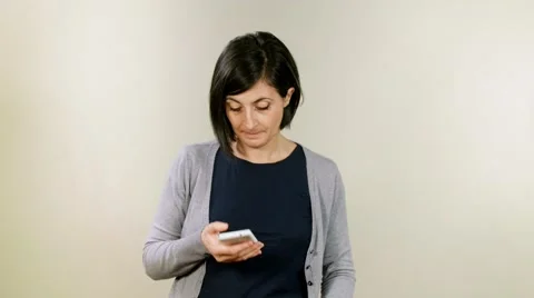 Young woman using smartphone in studio. Smiling, laughing and snorting Stock Footage 58945588