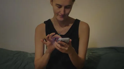 Young woman using smartphone in warm bedroom... Stock Footage 337971412
