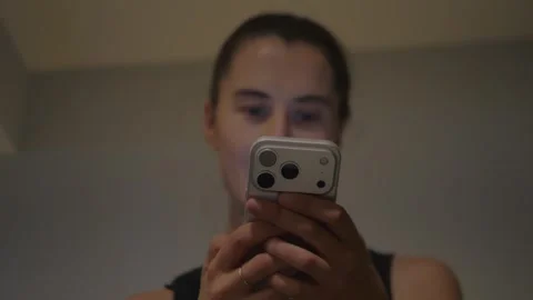 Young woman using smartphone in a warm bedroom. Focus on phone. Stock Footage 337971413