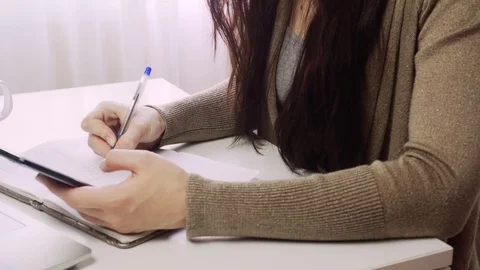 Young woman using smartphone while doing homework. 스톡 동영상 122728891