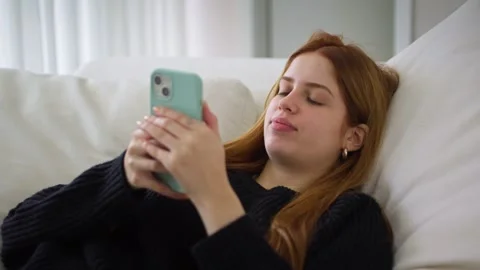 Young woman using smartphone while sitting on couch. Stock Footage 259899409