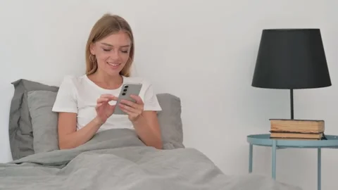 Young Woman Using Smartphone while Sitting in Bed Video stock 287900150