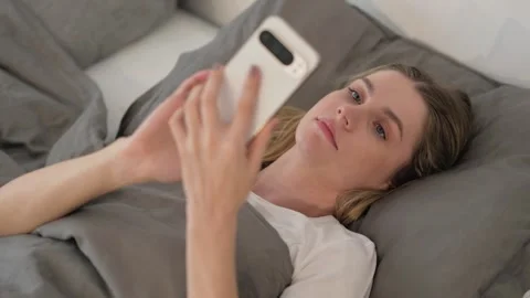 Young Woman Using Smartphone while Lying in Bed Video stock 299756987