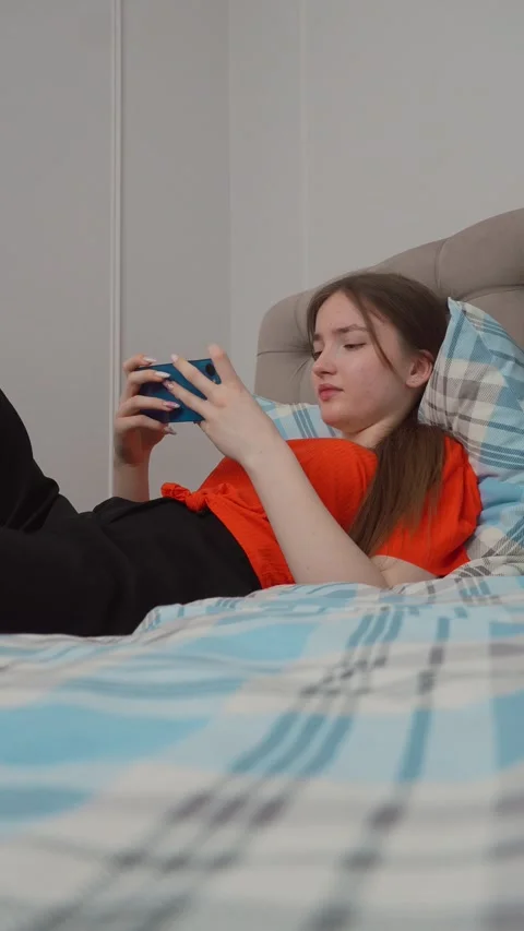 Young woman using smartphone while relaxing on bed Stock Footage 311779753