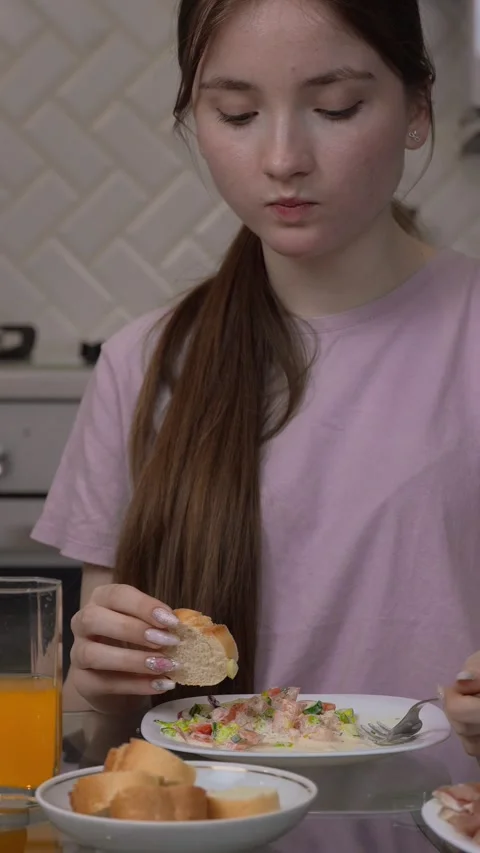 Young woman using smartphone while having breakfast in kitchen Stock Footage 311780412
