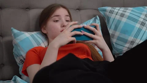 Young woman using smartphone while lying in bed Stock Footage 311806750