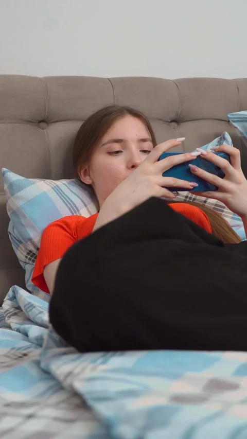 Young woman using smartphone while lying in bed Stock Footage 311815089