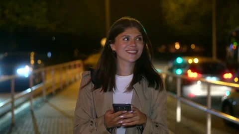 Young woman using smartphone while walking on city bridge at night Stock Footage 317376609