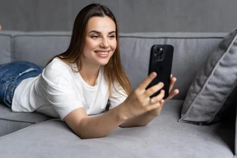 Young woman using smartphone while lying on sofa Foto stock