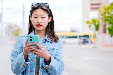 Young Woman Using Smartphone While Waiting at Tram Stop in the City,copy space Stock Photos