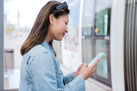 Young Woman Using Smartphone While Waiting for Tram to Board Stock Photos