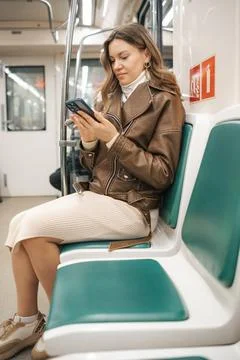 Young Woman Using Smartphone While Sitting on Subway Train in Modern Urban Stock Photos