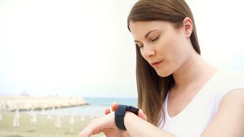 Young woman using smartwatch on beach alone. Female dictating message via smart Stock Footage 89701461