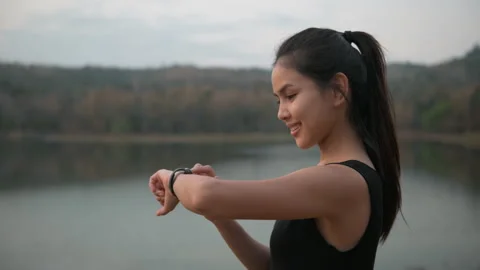 A young woman is using smartwatch while exercise in nature outdoor at sunset Stock Footage
