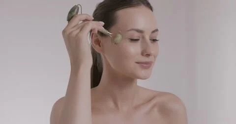 Young woman using stone roller for massaging skin under eyes Stock Footage 158732873