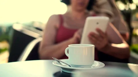 Young woman using tablet and drinking coffee outside on sunny morning. Видео 58279049