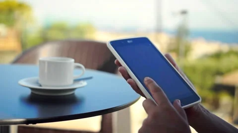 Young woman using tablet and drinking coffee outside on sunny morning. 動画素材 58279521