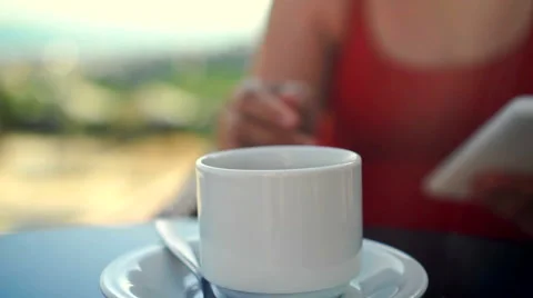 Young woman using tablet and drinking coffee outside on sunny morning. Stock Footage 58280036