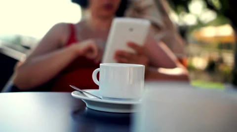 Young woman using tablet and drinking coffee outside on sunny morning. 库存影片 58280162