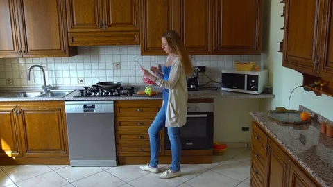 Young woman using tablet and cooking in kitchen Stock Footage 73755259