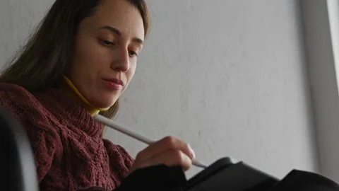 Young woman using tablet and stylus while sitting in chair Stock Footage 270363435