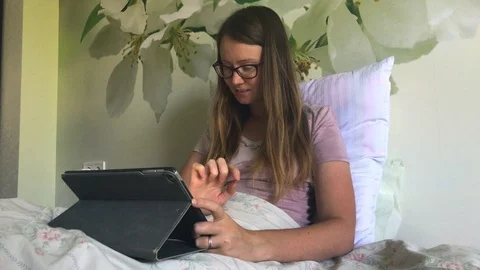 Young woman is using tablet in bed. Relaxing with modern technology. Stock Footage 94459757