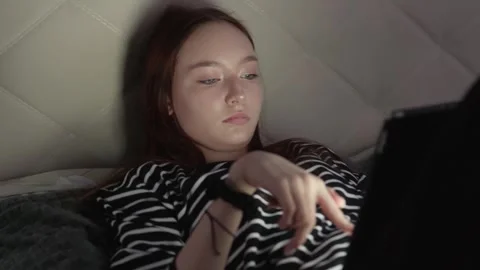 Young woman using tablet in bed at night Stock Footage 310748351
