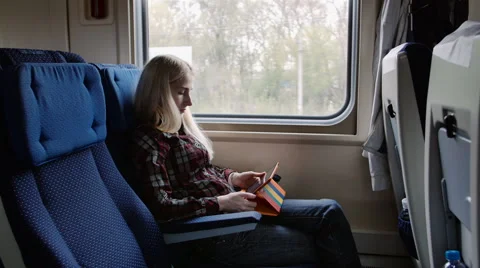 Young woman using tablet in colourful case while traveling by train Видео 62652924