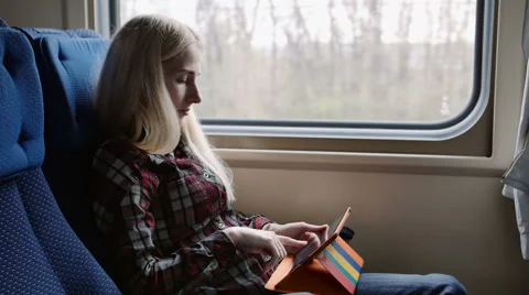 Young woman using tablet in colourful case while traveling by train Stock Footage 62653545