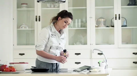 Young woman using tablet computer and cooking in kitchen at home  HD Vídeos de archivo 51848962