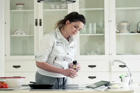 Young woman using tablet computer and cooking in kitchen at home  NTSC Vídeos de archivo 51848972