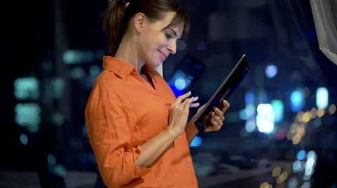 Young woman using tablet computer by window at home at night Stock Footage 56937075