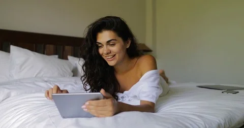 Young Woman Using Tablet Computer Happy Smiling Beautiful Girl Lying On Bed In Stock Footage