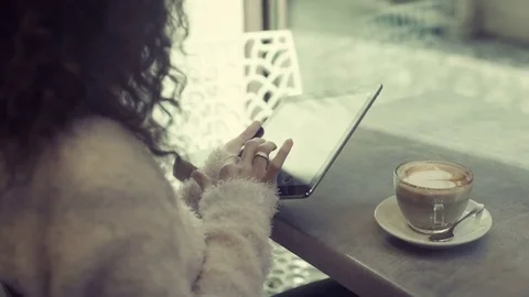 Young woman using a tablet computer sitting alone in a cafe Video stock 75549639