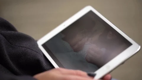 Young woman using tablet computer while sitting on bench in autumn park. Close Stock Footage 82837606