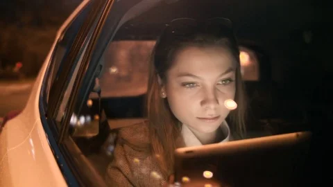 Young Woman Using a Tablet Computer in the Moving Car Stock Footage 84718667