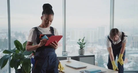 Young woman using tablet computer wearing cleaning uniform. Her caucasian male Stock Footage 149263726