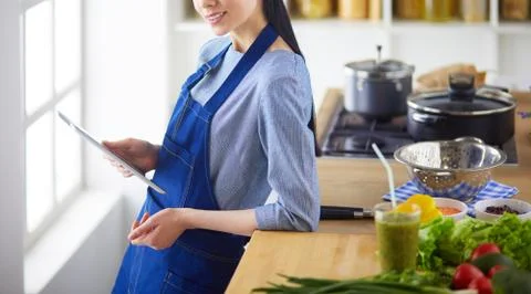 Young woman using a tablet computer to cook in her kitchen Stock Photos