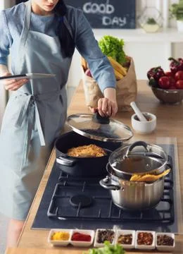 Young woman using a tablet computer to cook in her kitchen Stock Photos