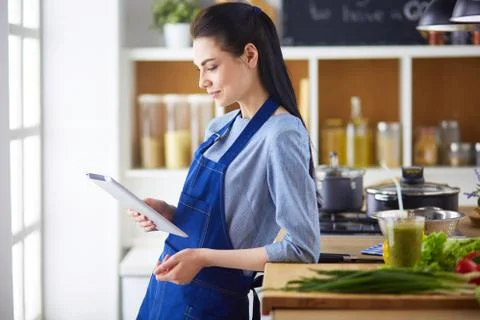 Young woman using a tablet computer to cook in her kitchen Stock Photos