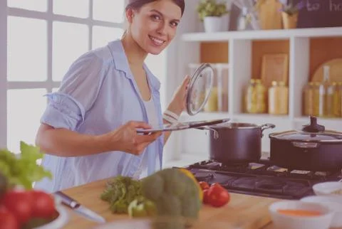 Young woman using a tablet computer to cook in her kitchen. Stock Photos