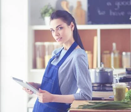Young woman using a tablet computer to cook in her kitchen Stock Photos