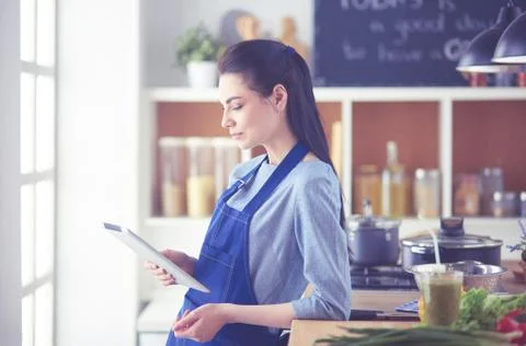 Young woman using a tablet computer to cook in her kitchen Stock Photos