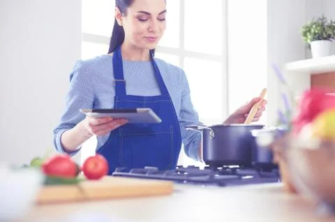 Young woman using a tablet computer to cook in her kitchen Stock-Fotos